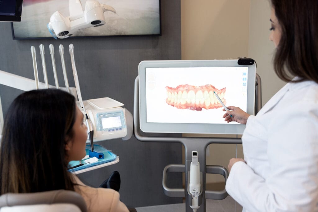 Dentist reviewing a 3D digital scan of a patient's teeth on a screen during an aligner consultation